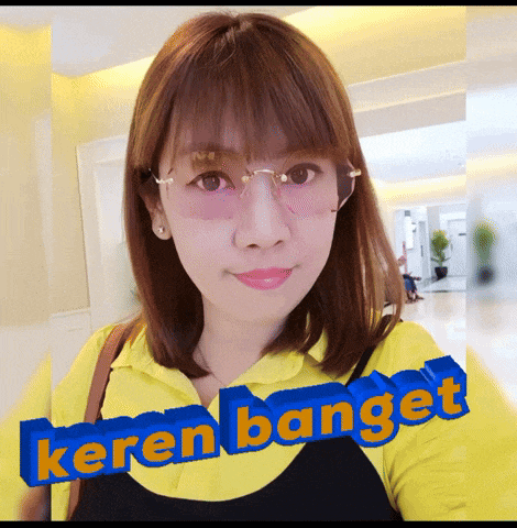 a woman wearing glasses and a yellow shirt has keren banget written in blue letters