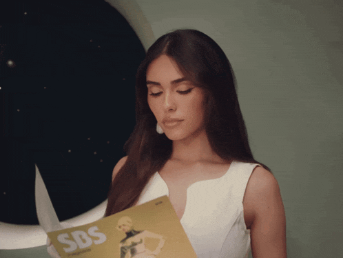 a woman in a white dress is holding a magazine that says sbs