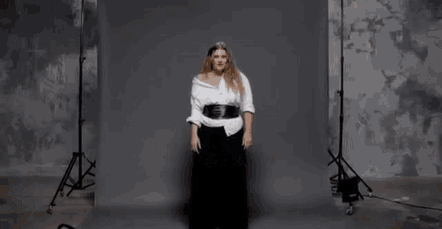 a woman with long hair is wearing a white shirt and a black skirt .