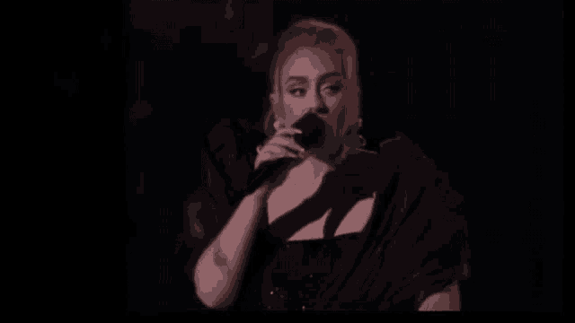 a woman is singing into a microphone and smiling