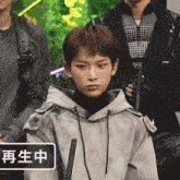 a young man in a hoodie is standing in front of a group of men .