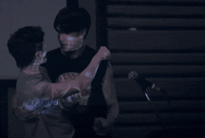a man is carrying another man in his arms while standing in front of a microphone