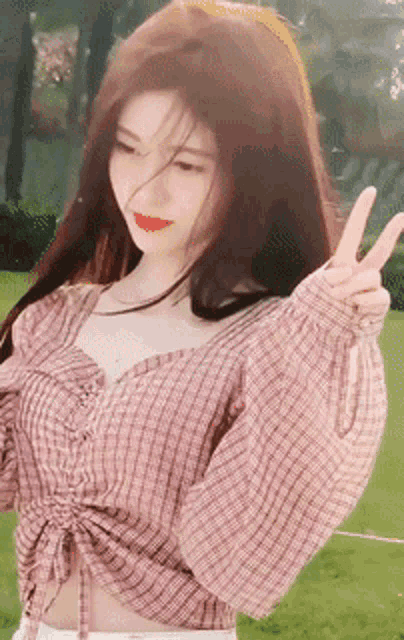 a woman in a plaid shirt is making a peace sign