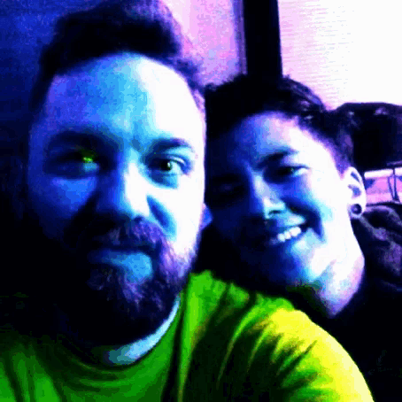 a man with a beard is smiling next to a woman in a green shirt