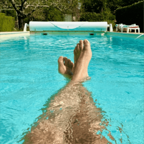 a person 's feet are in a swimming pool