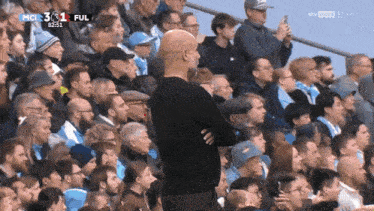 a man stands in front of a crowd watching a soccer game with the score being 3 to 1