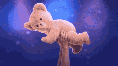 two hands holding a teddy bear in the air