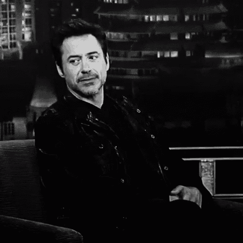 a black and white photo of a man in a leather jacket sitting on a couch