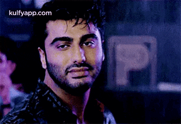 a close up of a man 's face with a beard and a purple background .