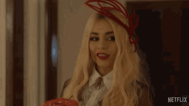 a woman with blonde hair and a red hat is standing in a room .