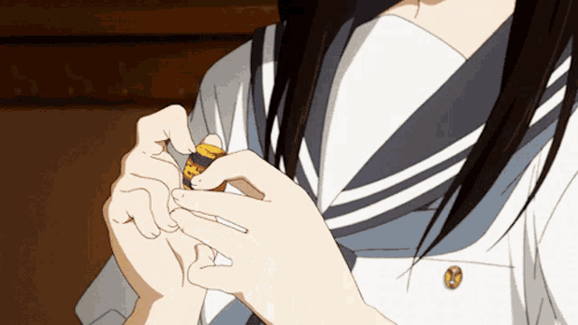 a girl in a sailor uniform is holding a small yellow object with the letter p on it