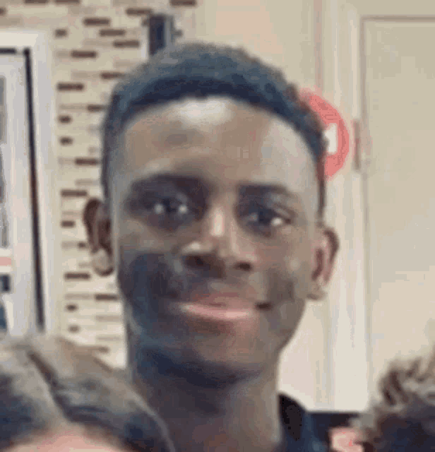 a young man is smiling for the camera in a crowd of people .