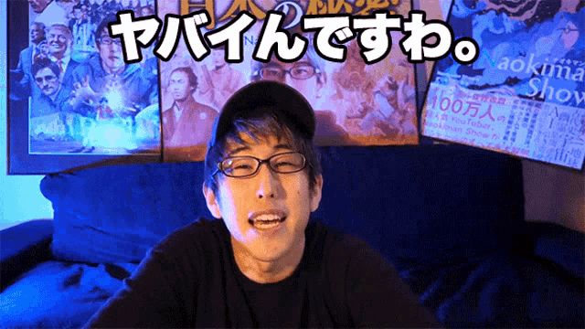 a man wearing glasses and a hat is sitting in front of a poster that says 100 million