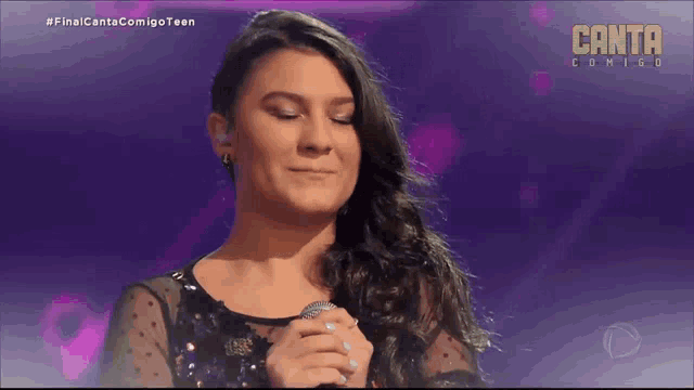 a woman singing into a microphone with the words canta coming on the bottom
