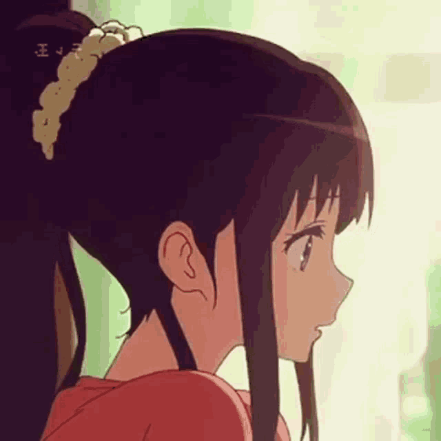 a close up of a girl 's face with a ponytail and a red shirt .