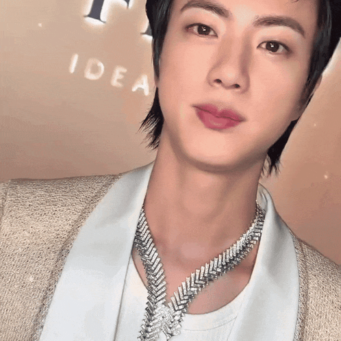 a close up of a man wearing a necklace in front of an idea sign