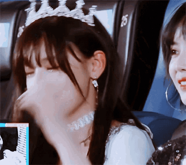 a woman wearing a tiara and a choker is sitting next to another woman in a car