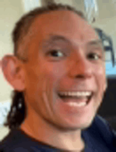 a close up of a man 's face with a ponytail smiling .