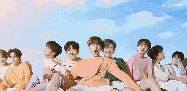 a group of young men are sitting in a row with a blue sky behind them