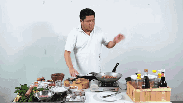 a man in a white shirt is cooking in a pan