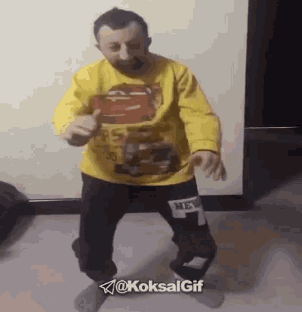 a man in a yellow cars shirt is dancing in a room