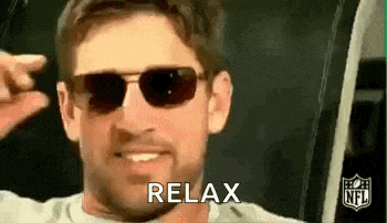 a man wearing sunglasses is smiling and making a peace sign with his hand .