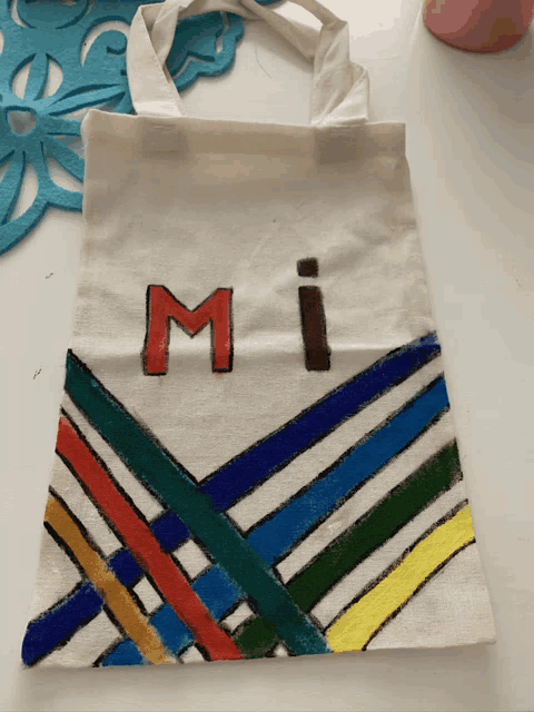 a white tote bag with the letter m painted in red