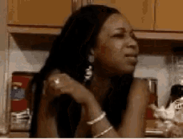 a woman is sitting in a kitchen with her hand on her shoulder