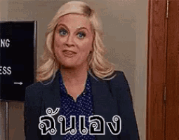 a woman in a suit and polka dot shirt is standing in front of a door and making a face .