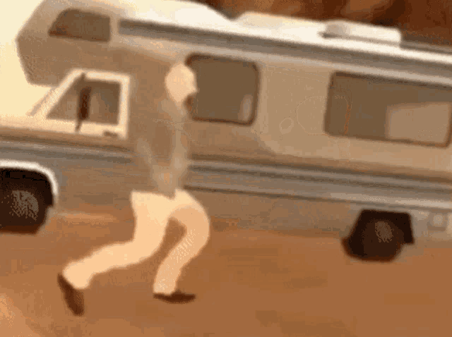 a man is running in front of a camper van in the desert .