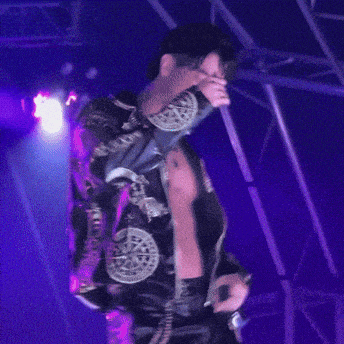 a man without a shirt is singing into a microphone on stage