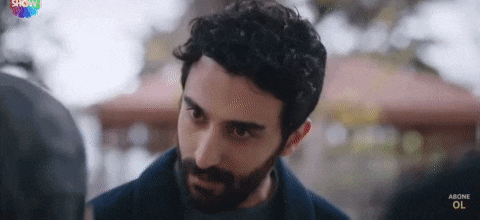 a man with a beard is looking at another man in a park .