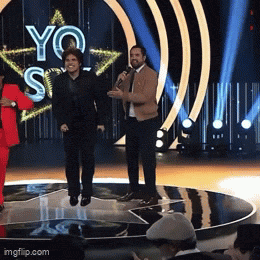 a group of people standing on a stage with a sign that says yo si