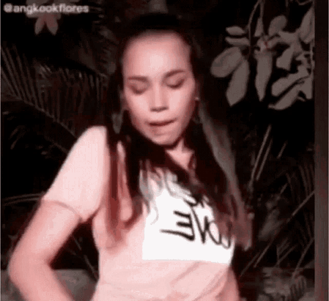a woman wearing a pink t-shirt with the word evo on it is dancing .