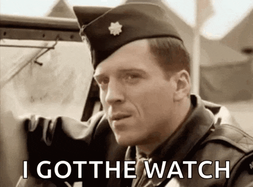 a man in a military uniform is sitting in a car with the words `` i got the watch '' written on the screen .