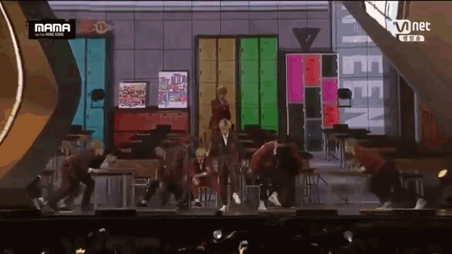 a group of people are dancing on a stage with a mnet logo in the background