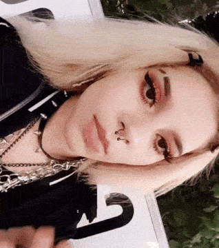 a close up of a woman 's face with a nose ring and a choker