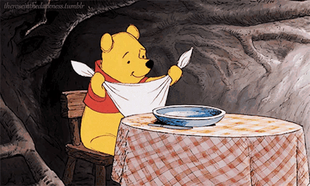 a cartoon of winnie the pooh sitting at a table with a checkered table cloth