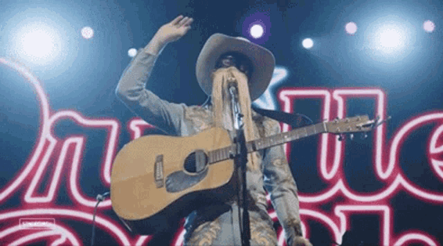 a man with long hair is playing a guitar and singing into a microphone .