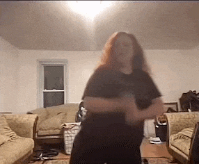 a woman is dancing in a living room with a couch .