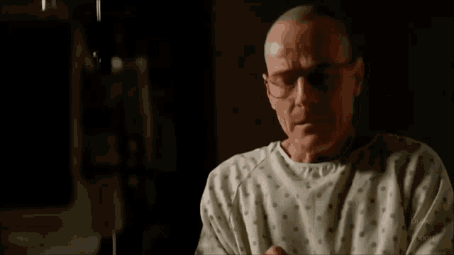 a man in a hospital gown is crying while sitting on a bed .