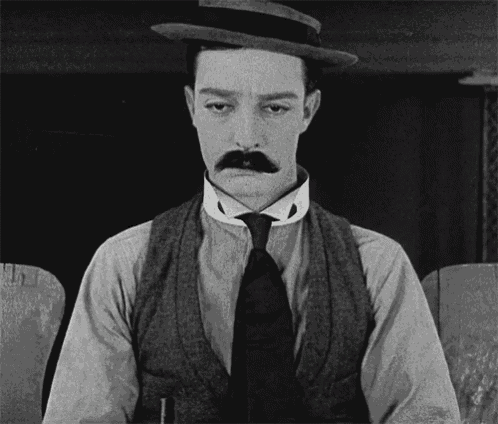 a black and white photo of a man with a hat and mustache