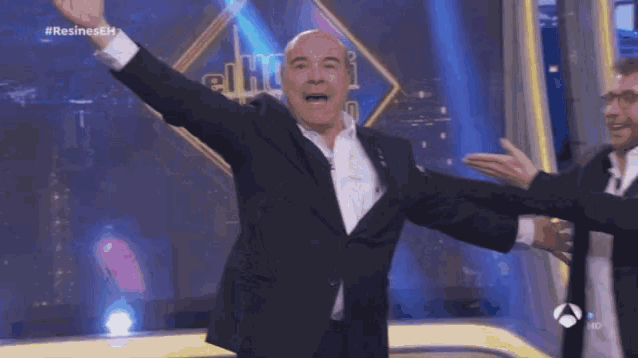 a man in a suit with his arms outstretched in front of a sign that says el hofi