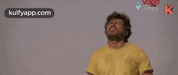 a man with a beard wearing a yellow shirt is laughing .