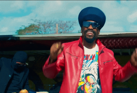 a man wearing sunglasses and a red jacket has a t-shirt that says ' reggae ' on it