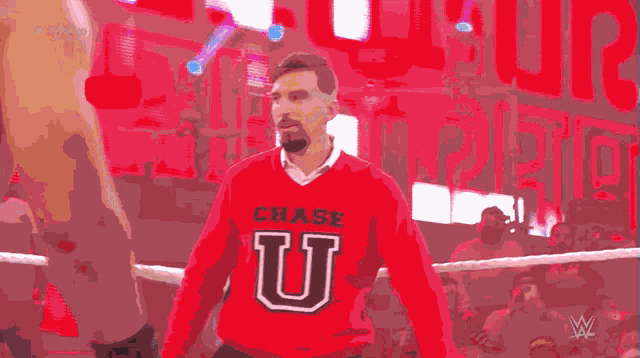 a man wearing a red chase u sweater stands in front of a crowd