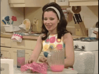 a woman in a polka dot dress is sitting at a table in a kitchen