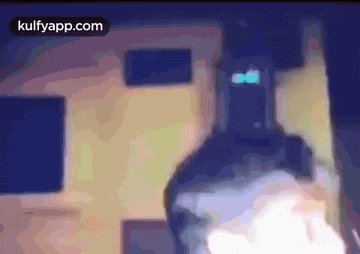 a blurred image of a person standing in front of a building with the website kulfyapp.com visible in the corner .