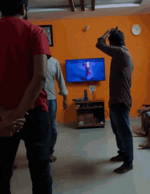 a man in a red shirt stands in front of a tv