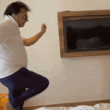 a man in a white shirt and blue pants is jumping in the air .